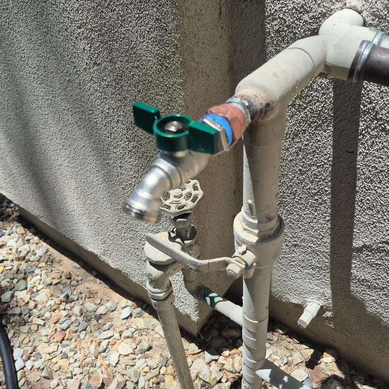Outdoor hose bib with green handle and piping