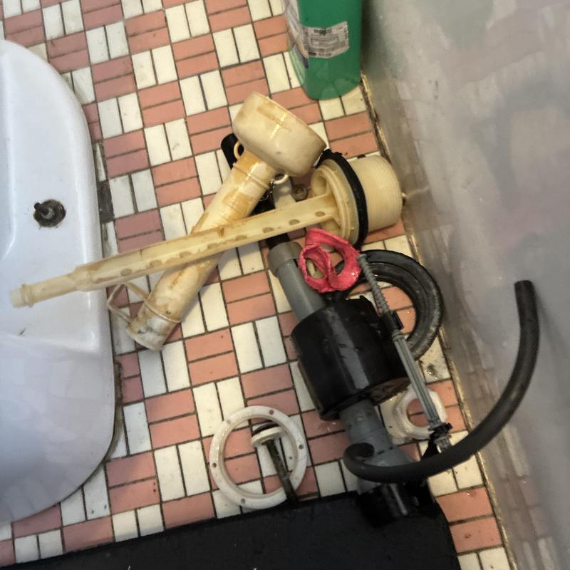 Toilet flush valve and tank parts on tiled floor