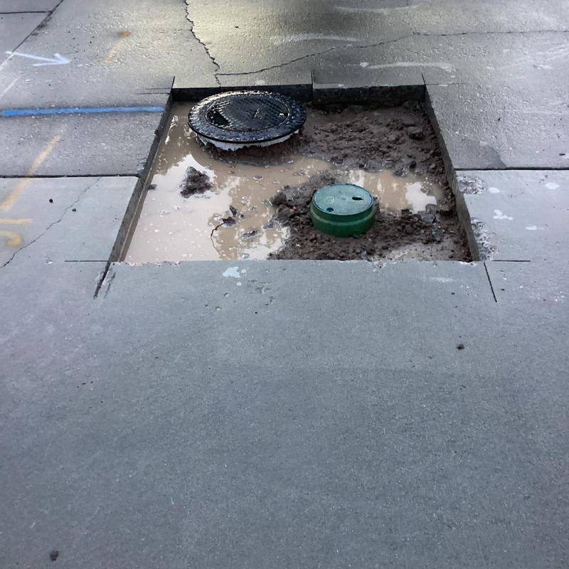 Water main excavation under broken concrete slab with water pooling Water main excavation under broken concrete slab with water pooling