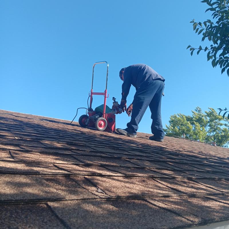 Mainline clog snaking through roof vent with plumber