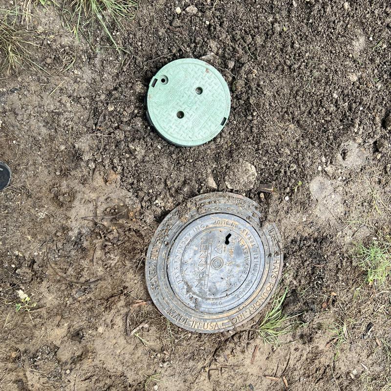 Valve box and water meter covers in dirt ground