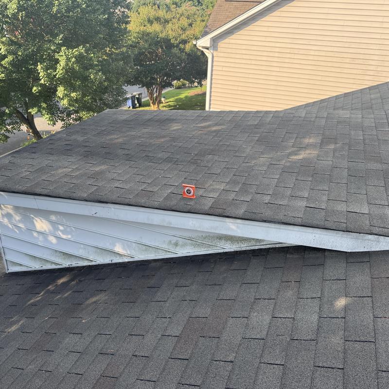 Asphalt shingle roof with hail damage marker on garage roof