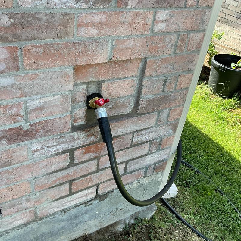 14-turn hose bib with attached garden hose on brick wall