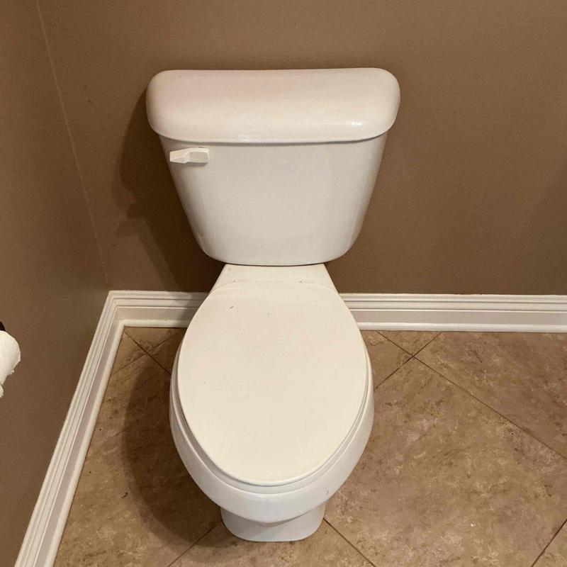 Guest bathroom toilet with flush lever on beige tile