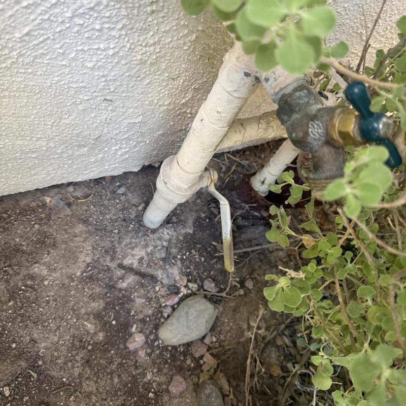 Outdoor water shutoff valve with piping near foundation