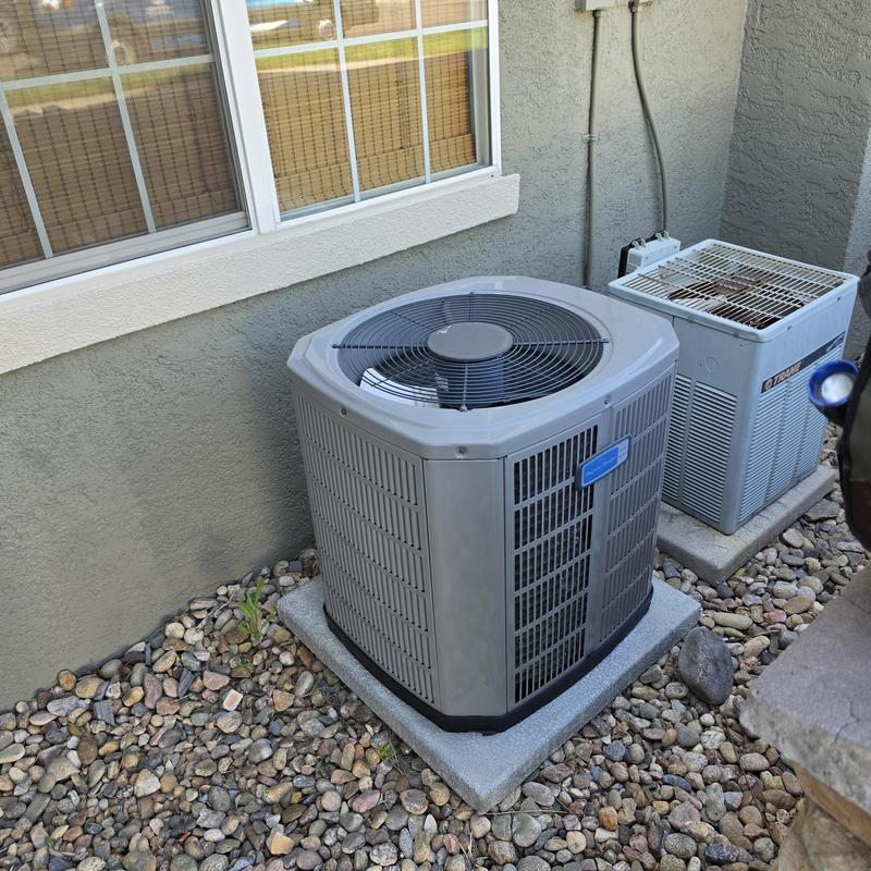 American Standard air conditioner unit outdoors near wall