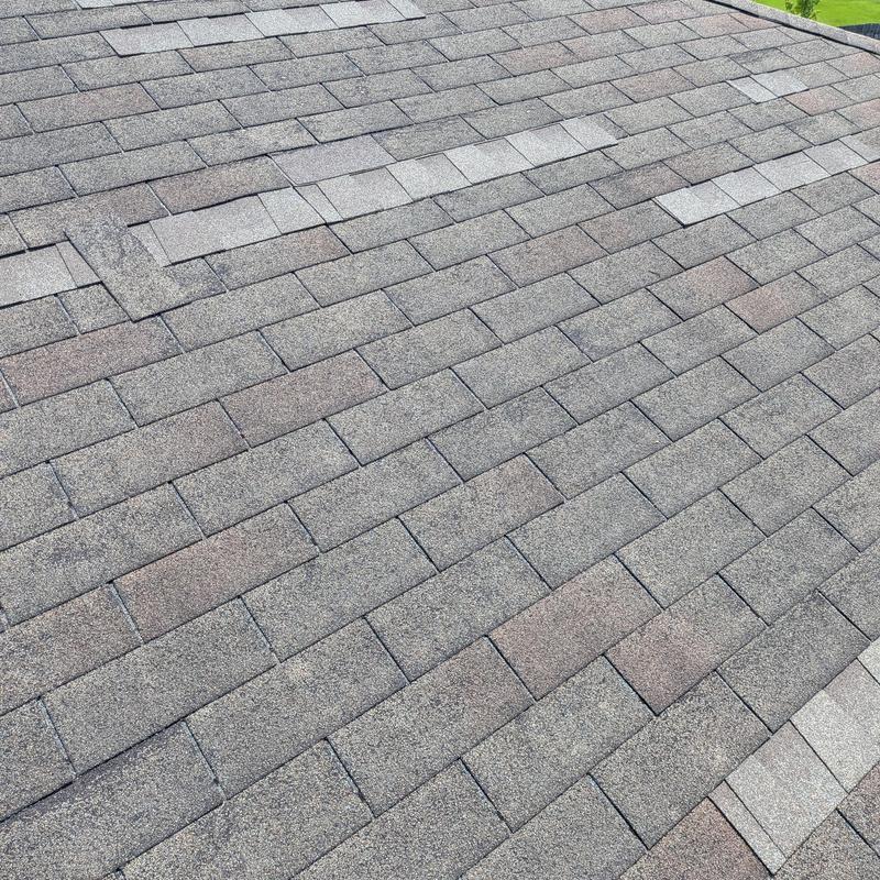 Asphalt shingle roof with patched and mismatched shingles
