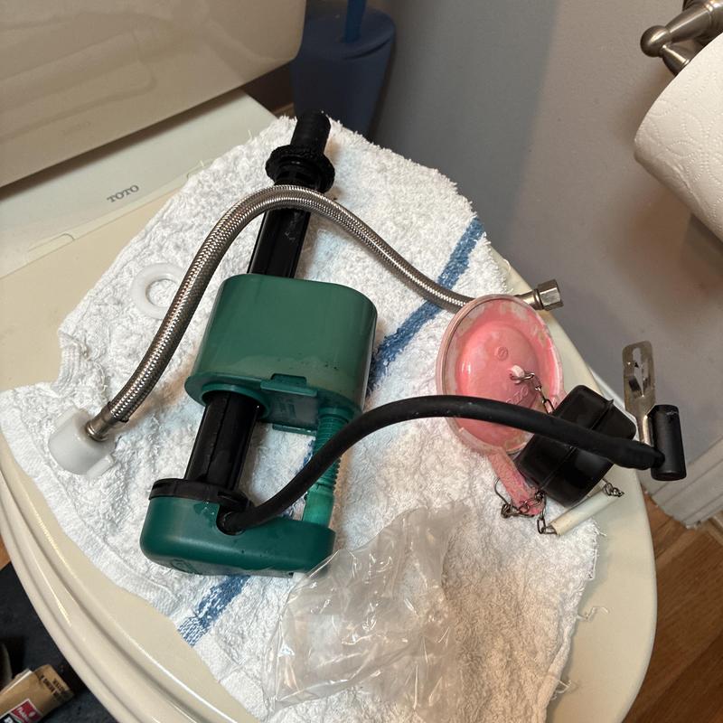 Toilet fill valve, flapper, and supply line parts on towel