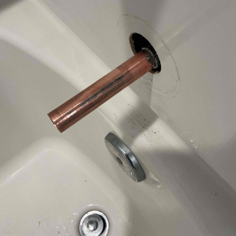 Copper diverter pipe protruding from bathtub wall