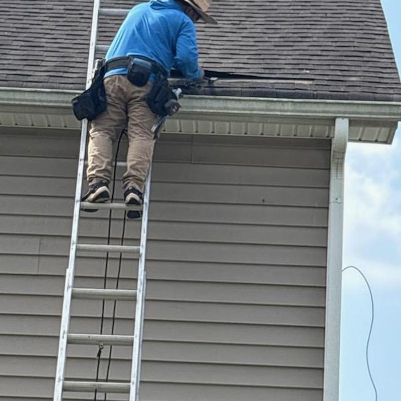 Roof shingles with plumbing pipe boot repairs on ladder