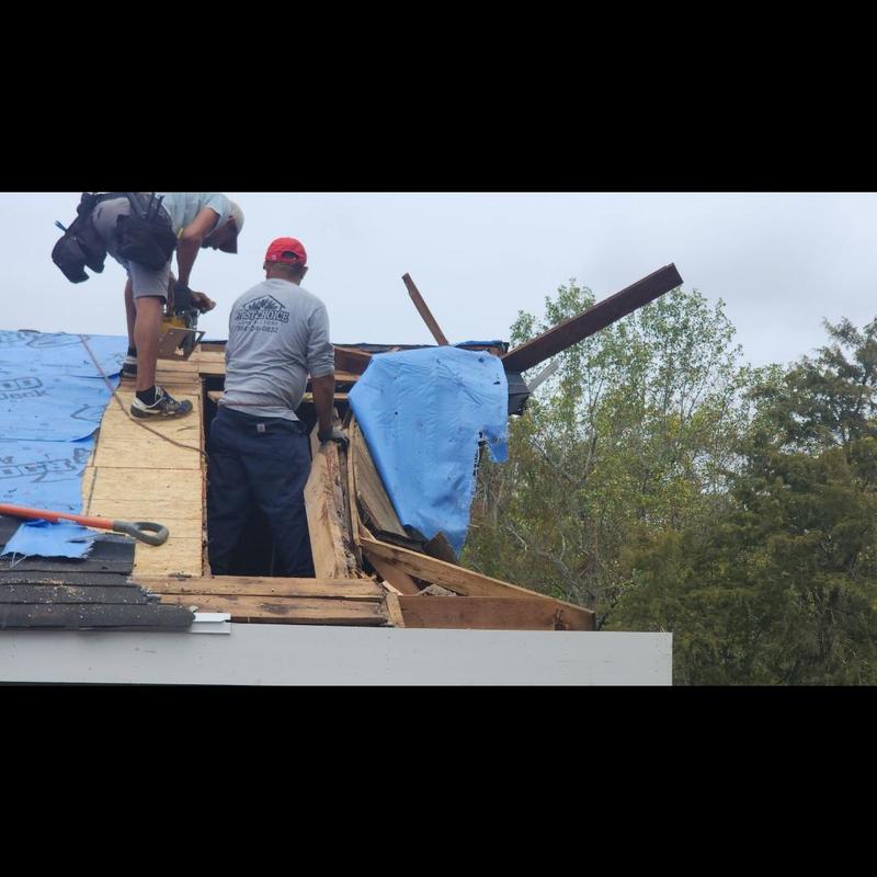 Barn roof decking structural rebuild with blue tarp