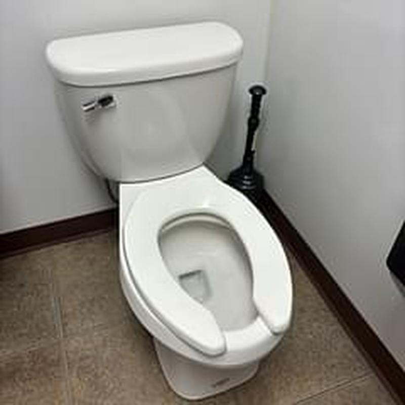 Toilet bowl and tank with plunger in daycare restroom Toilet bowl and tank with plunger in daycare restroom