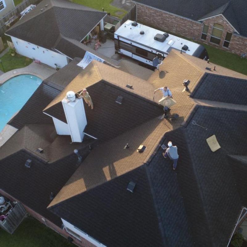 Asphalt shingle roof with workers performing maintenance