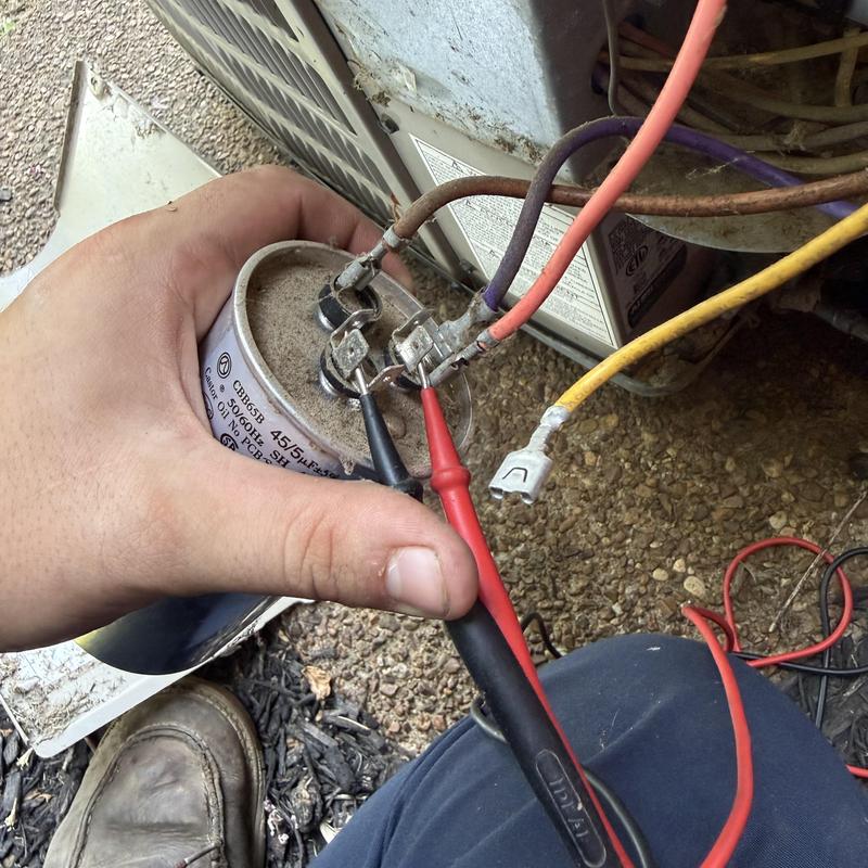 HVAC capacitor testing with multimeter probes outdoors HVAC capacitor testing with multimeter probes outdoors