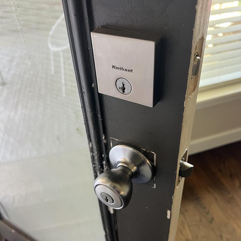 Kwikset deadbolt and door knob locks on black door