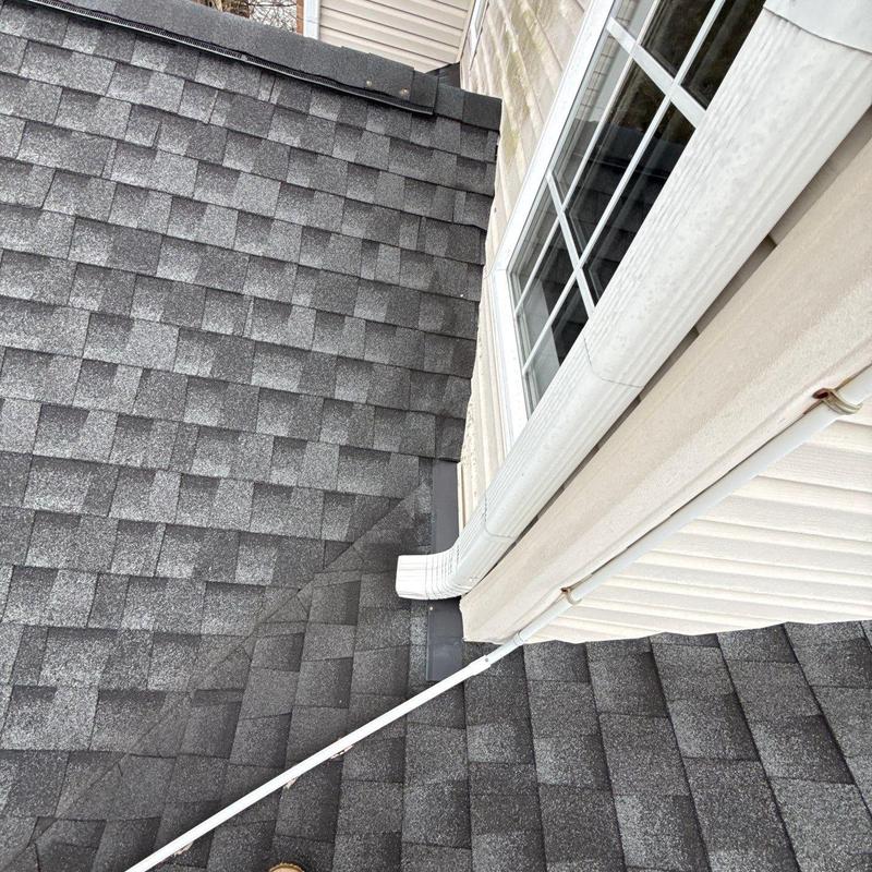 Asphalt shingle roof and gutter downspout corner detail