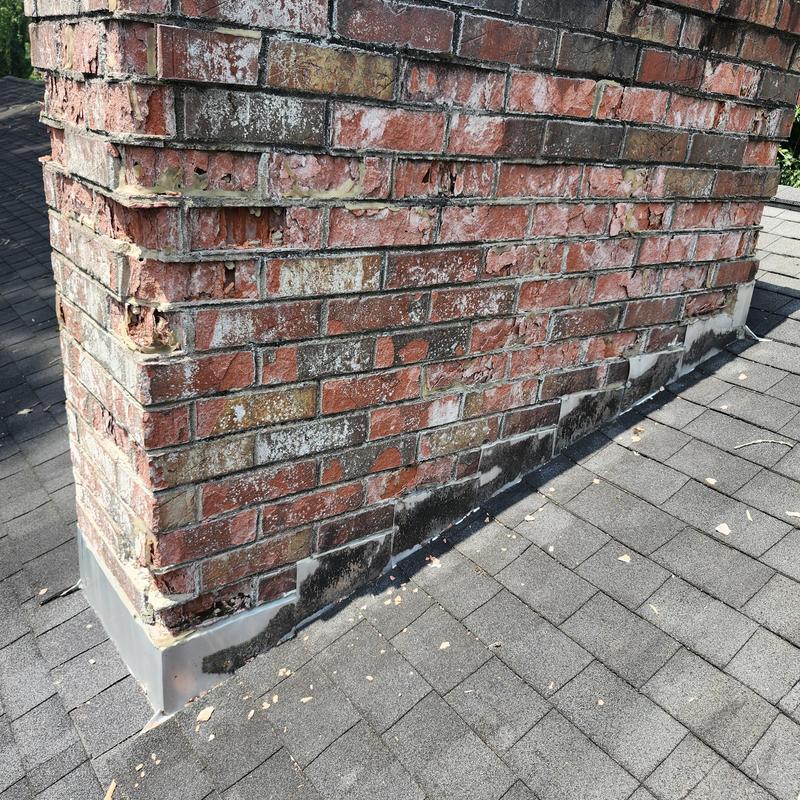 Brick chimney flashing with roof shingles and damaged mortar Brick chimney flashing with roof shingles and damaged mortar