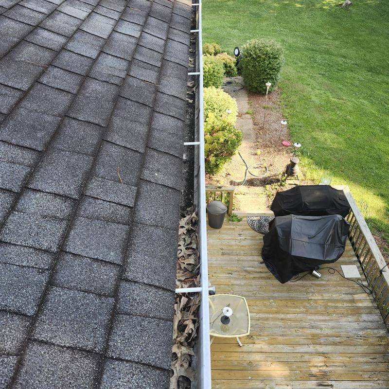 Gutter with leaves on asphalt shingle roof near deck Gutter with leaves on asphalt shingle roof near deck