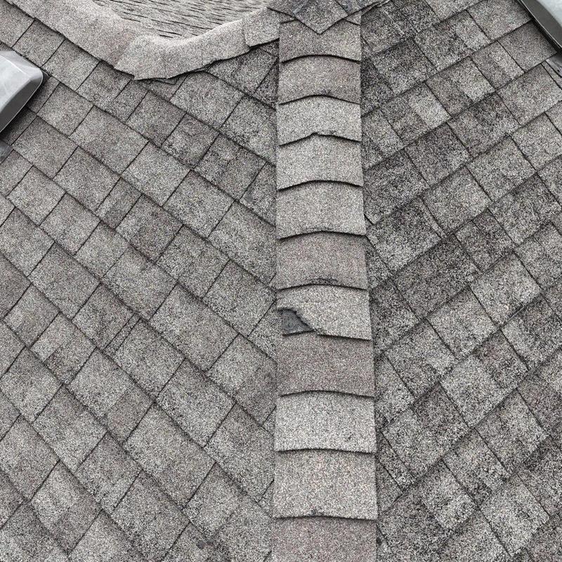 Roof shingles and ridge cap with visible wear and damage