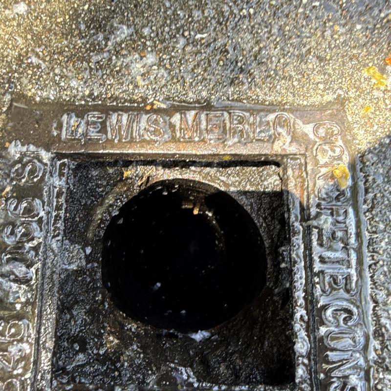 Sewer cleanout opening with metal frame on pavement