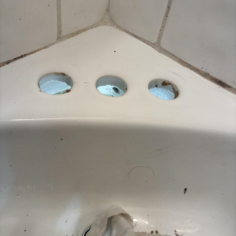 Bathroom sink faucet holes with chipped paint and corrosion