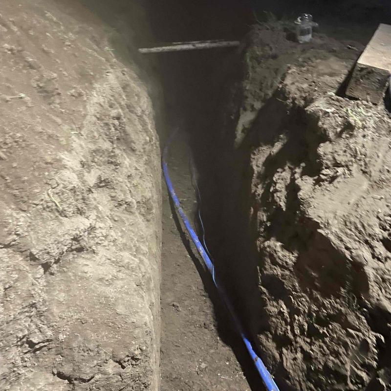 Main water line pipe installation in trench at night Main water line pipe installation in trench at night