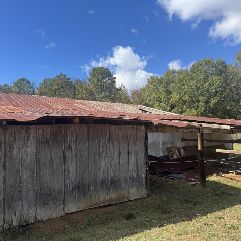 Metal roof with damaged wooden framing on barn exterior
