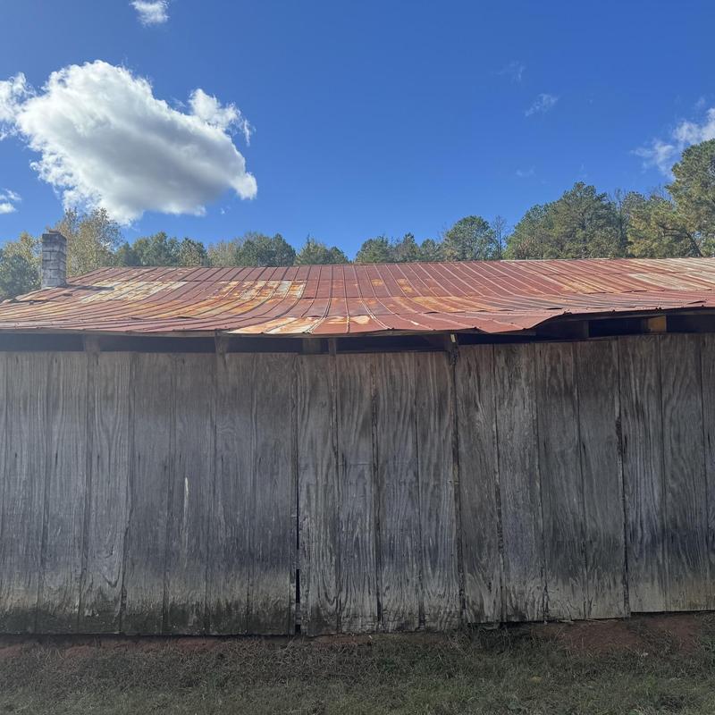 Metal roof with rust and damaged wood siding