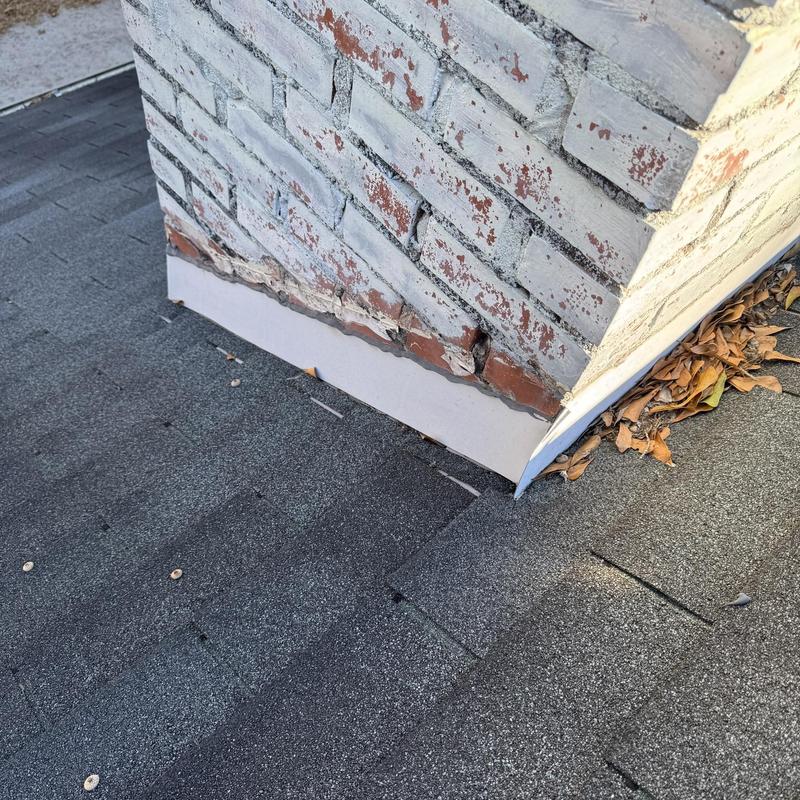 Chimney flashing and asphalt shingle roof with debris