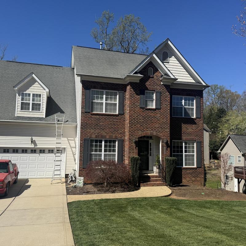 Roof shingles inspection with ladder by brick house