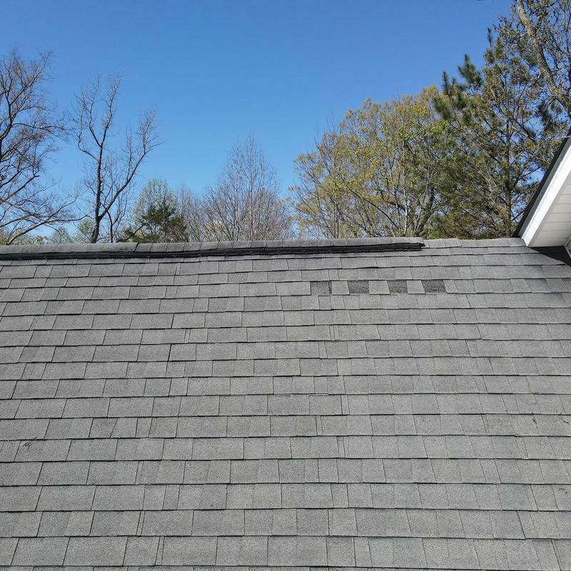 Asphalt roof shingles with hail damage and lifted ridge cap