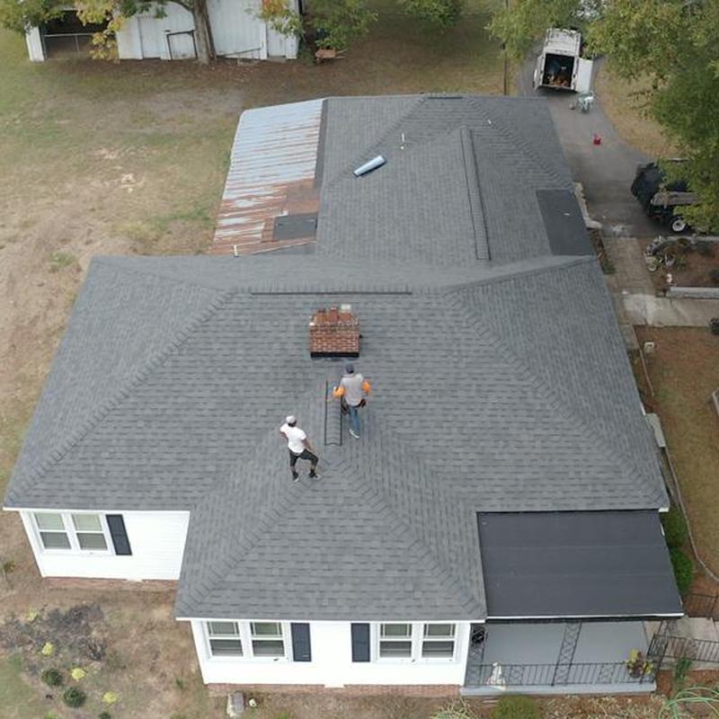 Roof shingles and chimney work with workers on site