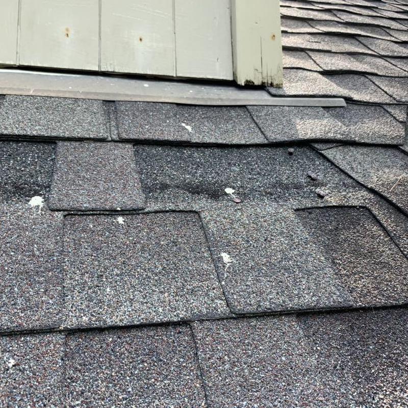Asphalt roof shingles near dormer flashing damage