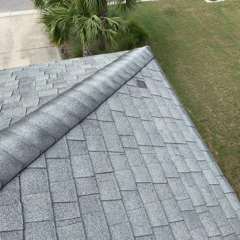 Roof shingles with replaced damaged section on steep roof