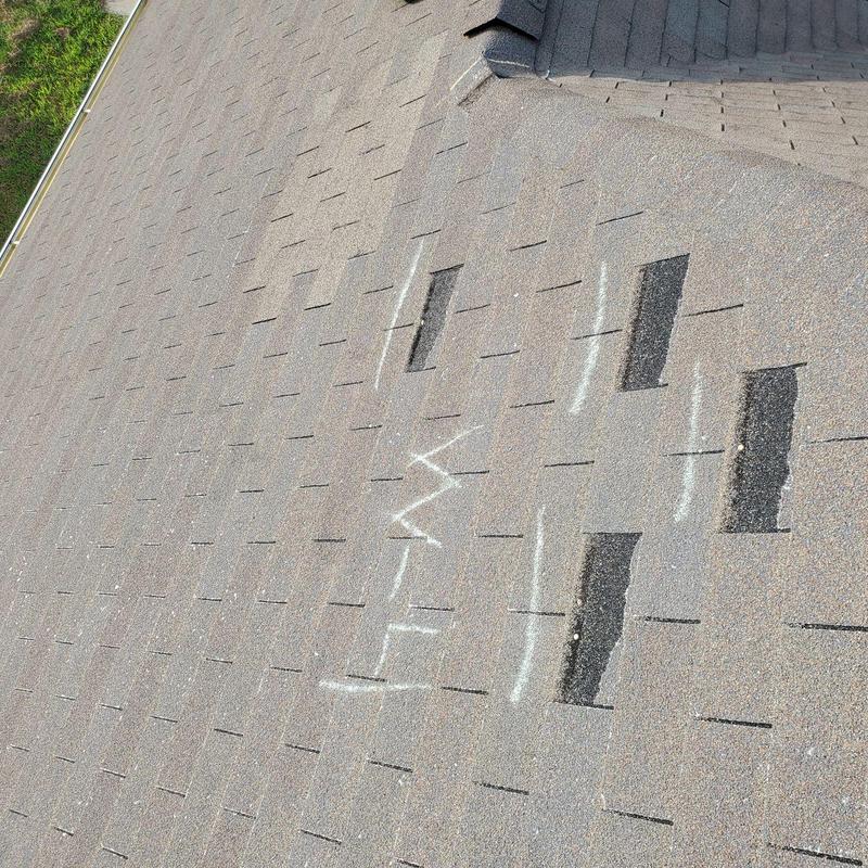 Asphalt shingle roof with marked damaged spots