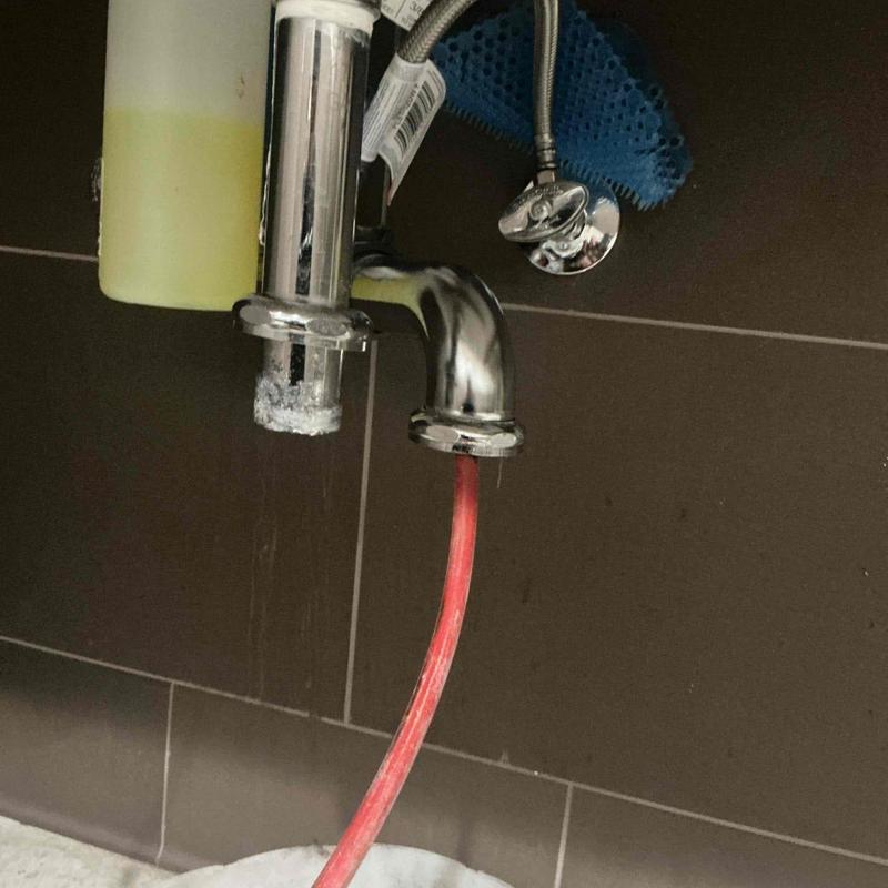 Sink drain line with red mechanical snake tool inserted