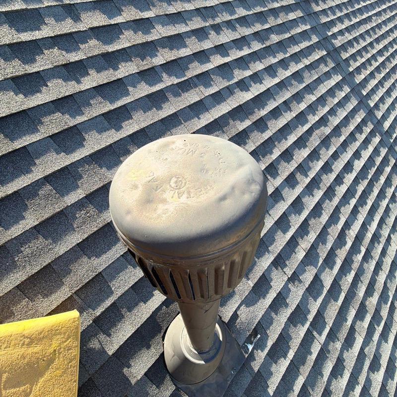 Roof vent with hail impact dents on asphalt shingles