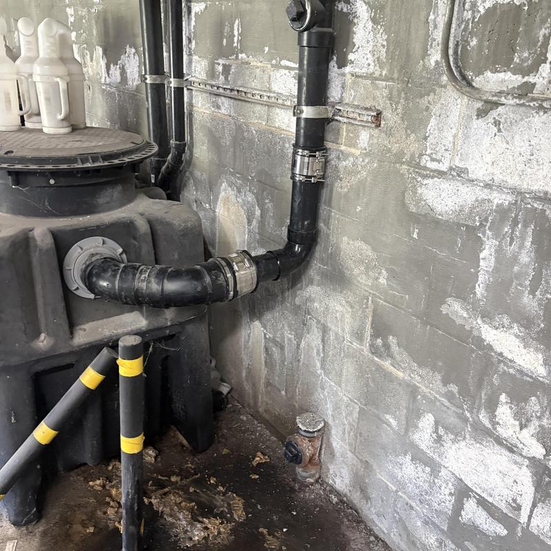 Grease interceptor mainline piping with clamps on wall