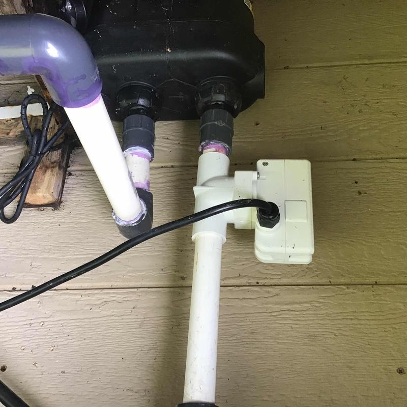 Chlorine pump with connected white PVC piping and wiring