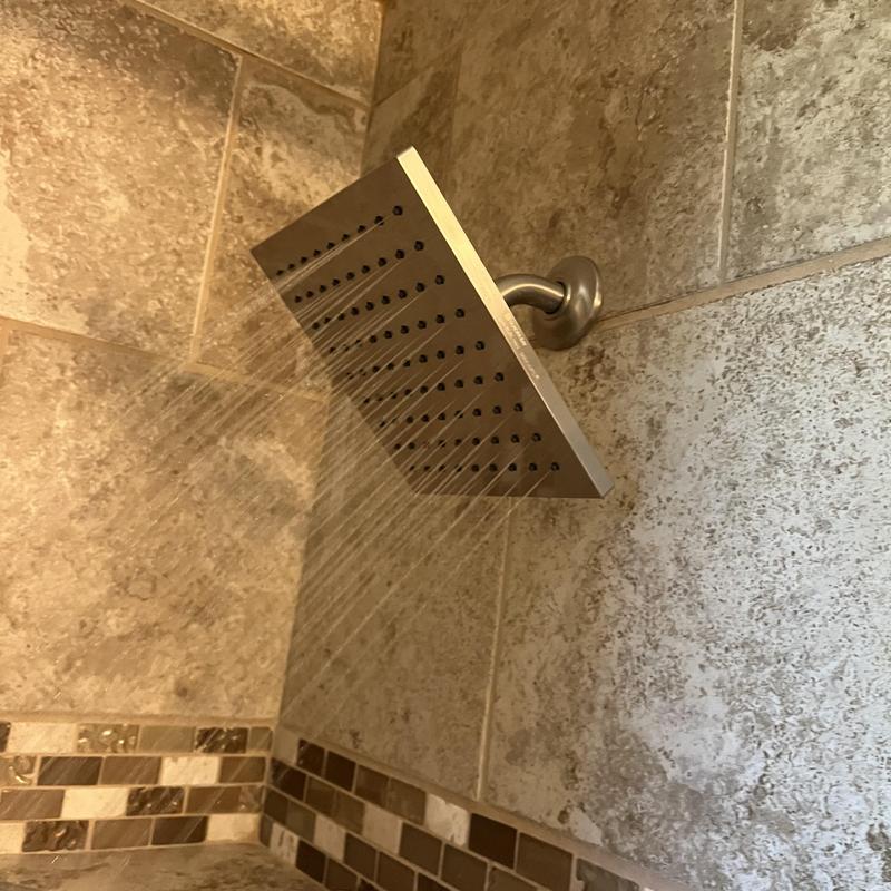 Square shower head with water flow in tiled bathroom Square shower head with water flow in tiled bathroom