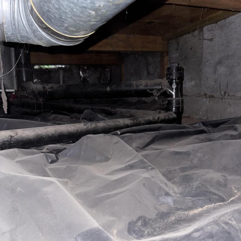Sewer drain pipes in crawl space with plastic vapor barrier