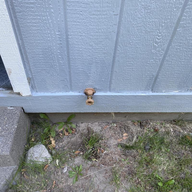 Yard hydrant hose bib on house exterior wall
