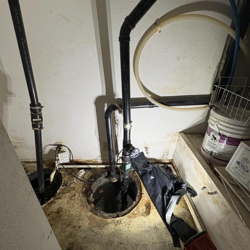 Sump pump and drainage pipe inspection in basement corner