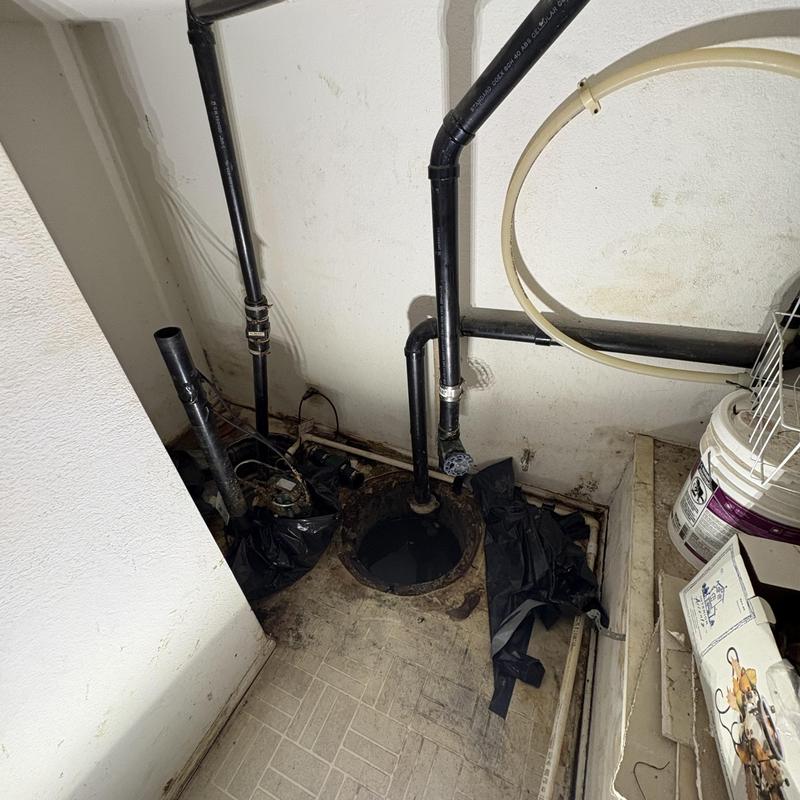 Sump pump basin with connected plumbing pipes