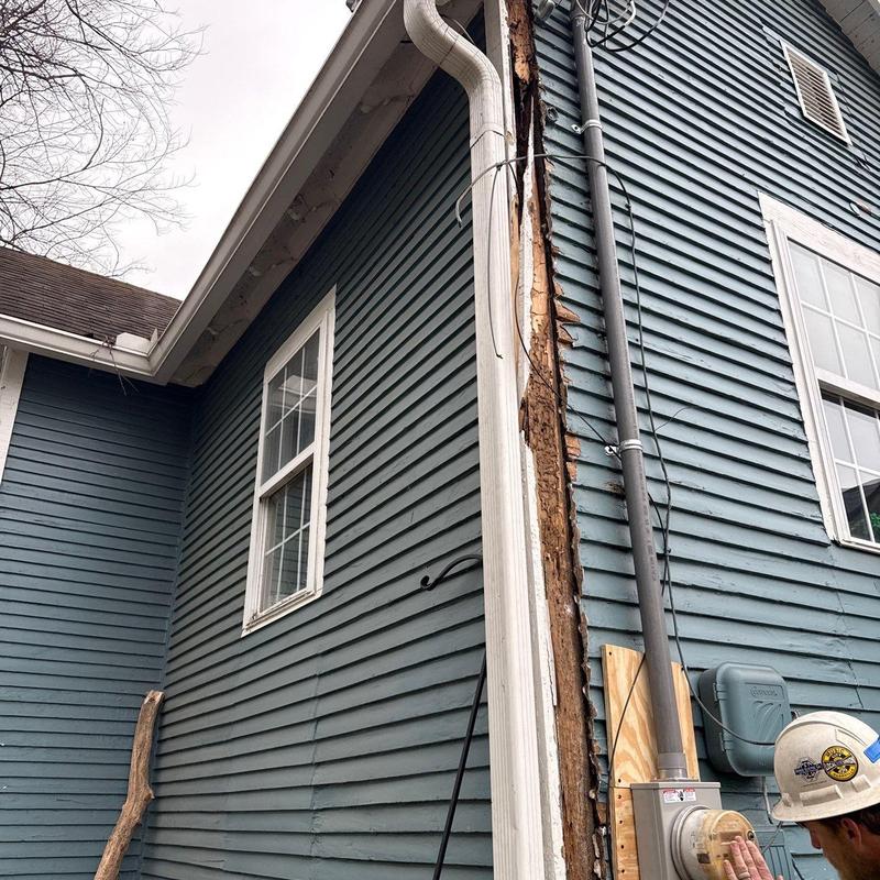 Exterior siding and gutter damage with wood rot on house