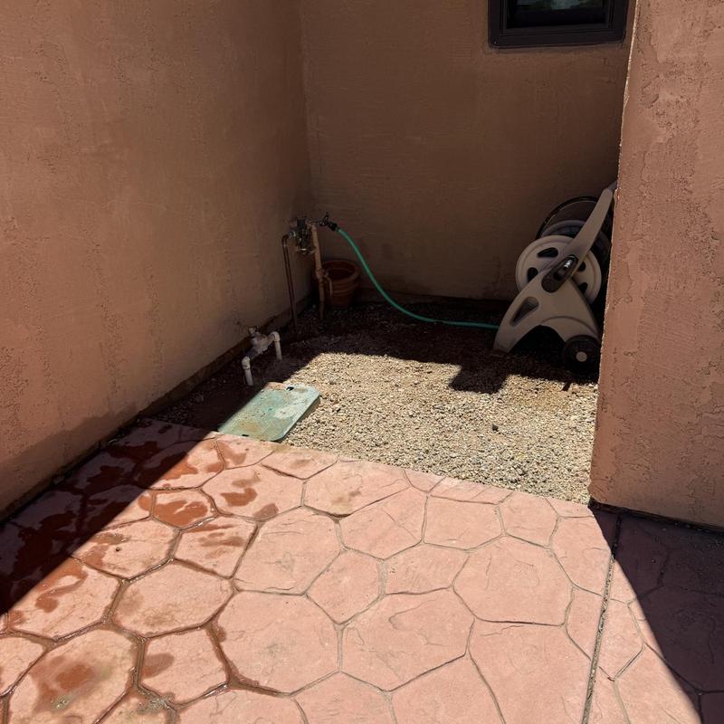 Outdoor water valve and hose reel setup in corner
