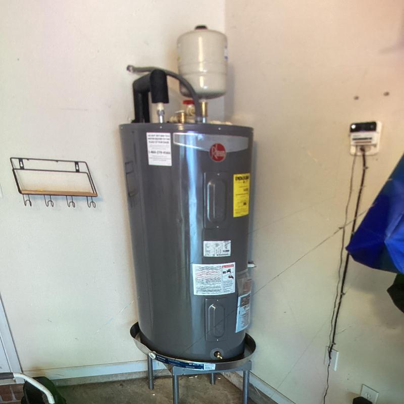 Electric water heater installed on stand in garage Electric water heater installed on stand in garage