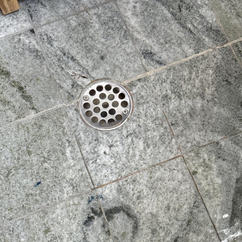 Shower drain with metal grate on tiled floor