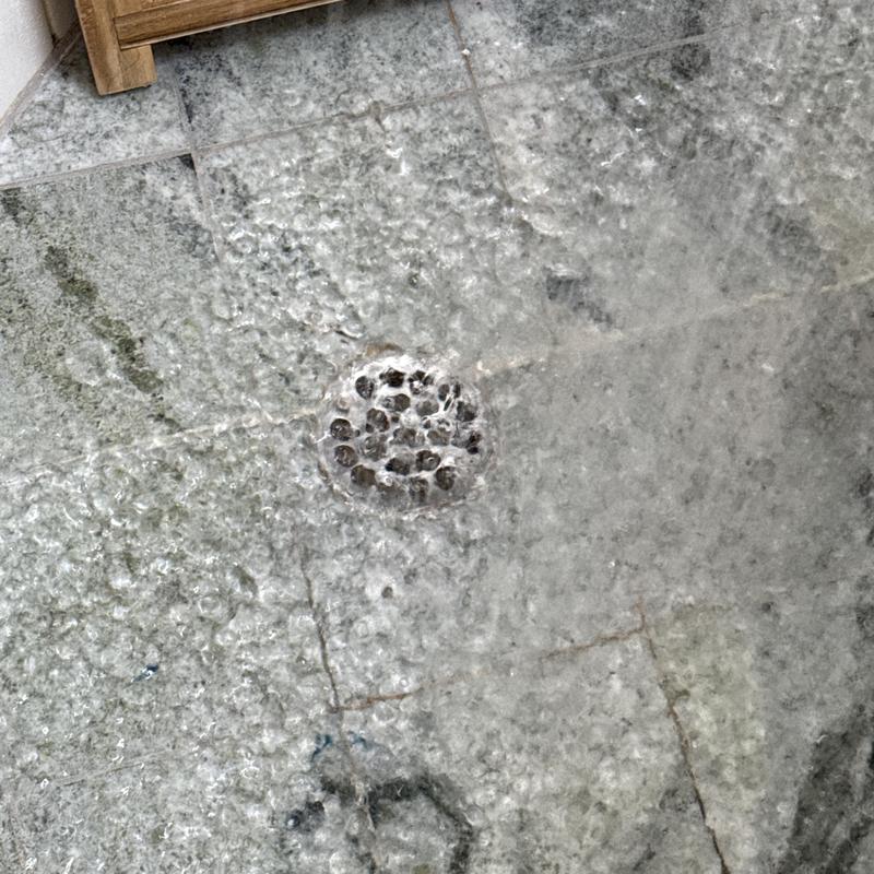 Shower drain with flowing water clearing blockage