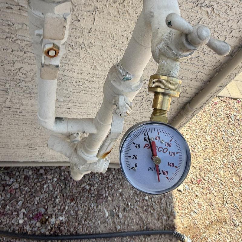 Outdoor water pipe with pressure gauge reading psi